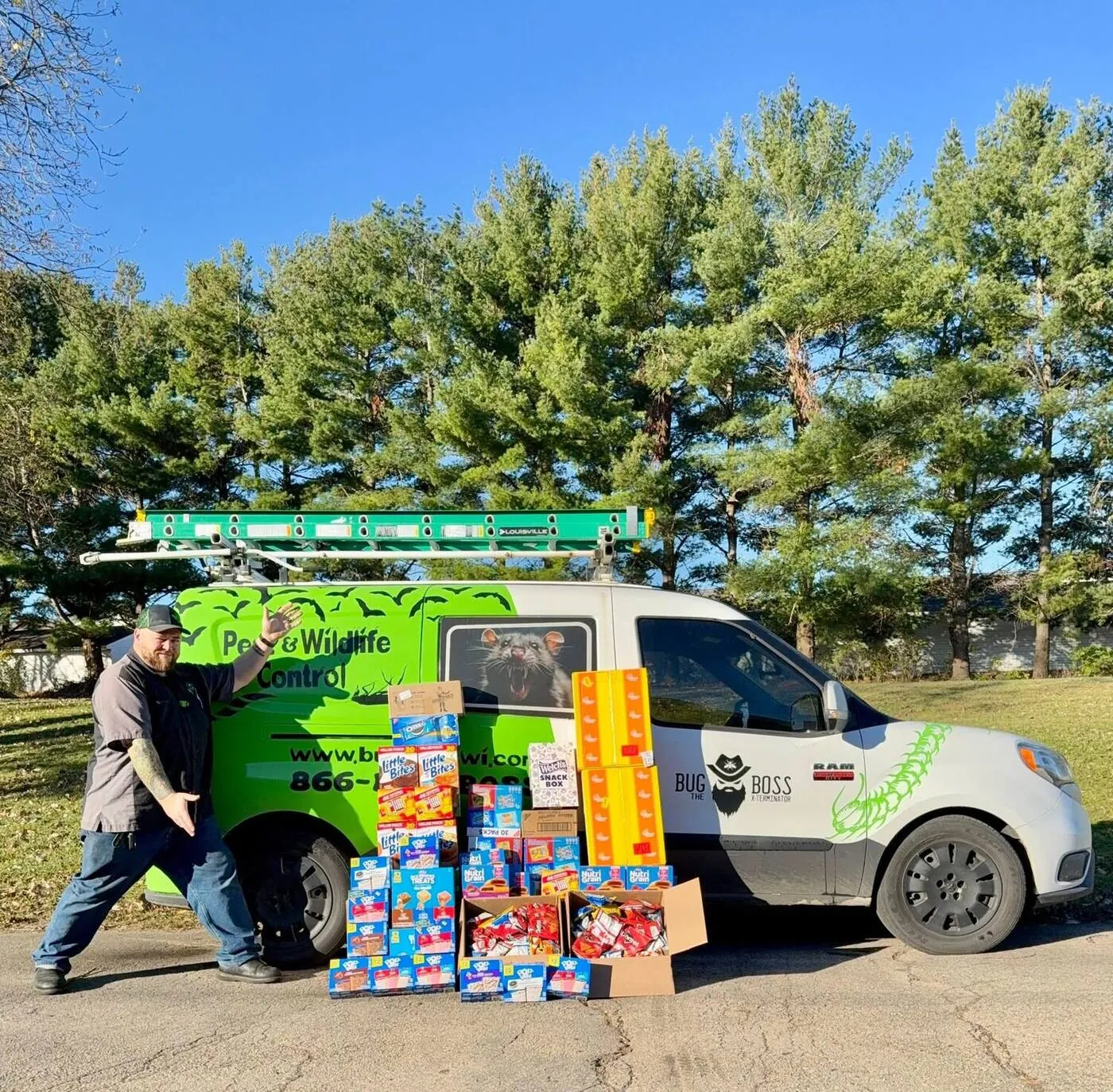 Brian beside the BugBoss wildlife-control van with boxes of donated snacks for a community drive