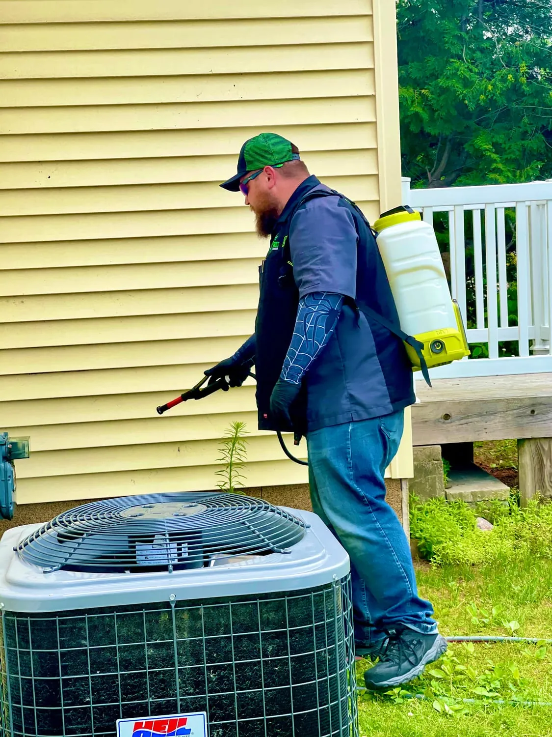 BugBoss treating the exterior around a home and AC unit for mosquitoes and ticks